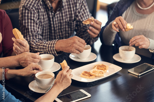 Fototapeta Naklejka Na Ścianę i Meble -  Cropped image of seniors having coffee and cookies for breakfast
