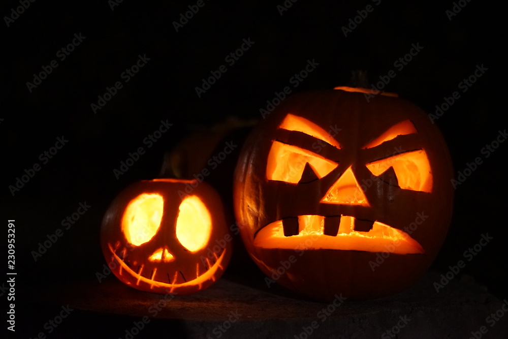 Carved scary halloween pumpkins jack-o-lantern on black background with candles inside Carved scary halloween pumpkins jack-o-lantern on black background with candles inside