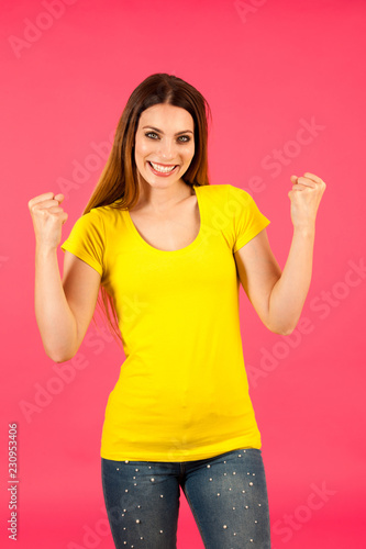 Funky young woman in yellow t shirt pose over pink background