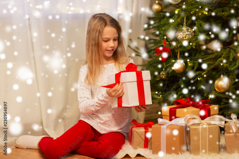 christmas, holidays and childhood concept - smiling girl with gift box at home christmas, holidays and childhood concept - smiling girl with gift box at home