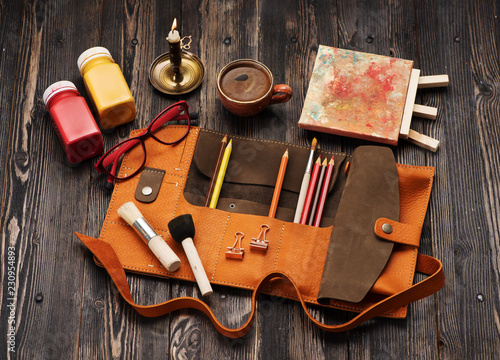 Leather case with colored pencils, brushes and paint for drawing..Accessories for painting and creativity, flat lay