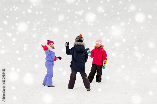 childhood, leisure and season concept - group of happy little kids in winter clothes playing outdoors