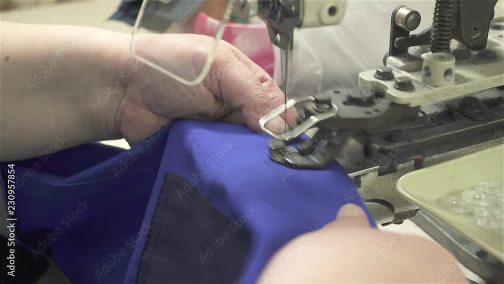 tailor sews buttons to overalls on a special machine tailor sews buttons to overalls on a special machine
