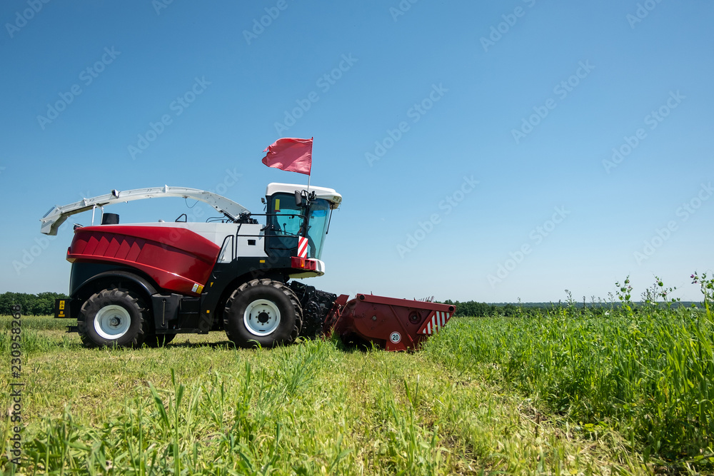Fototapeta premium heavy powerful red harvester in the field during the demonstration