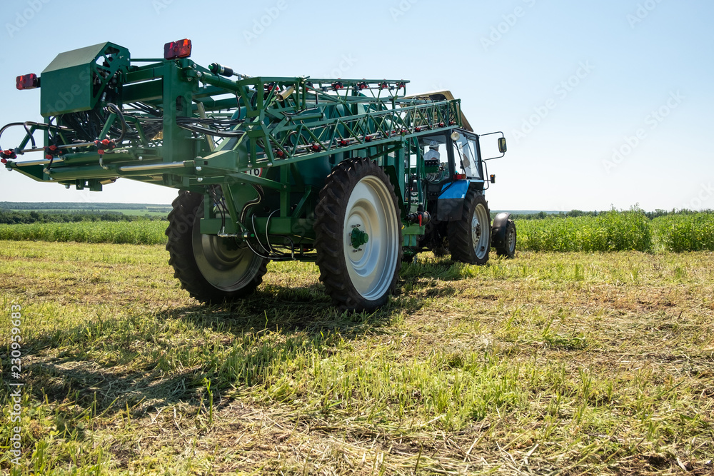 Fototapeta premium blue tractor in the field is preparing for chemical treatment of plants
