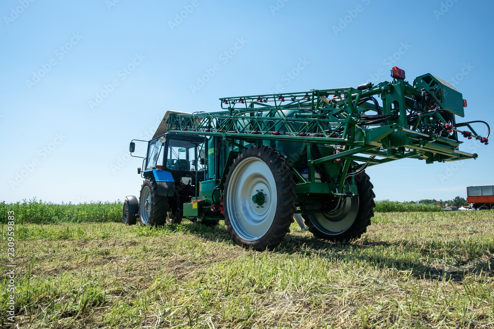 Fototapeta premium blue tractor in the field is preparing for chemical treatment of plants