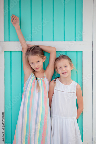 Adorable little girls on summer vacation background traditional colorful caribbean house