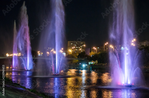 Colored luminous fountains in the middle of the lake at night.