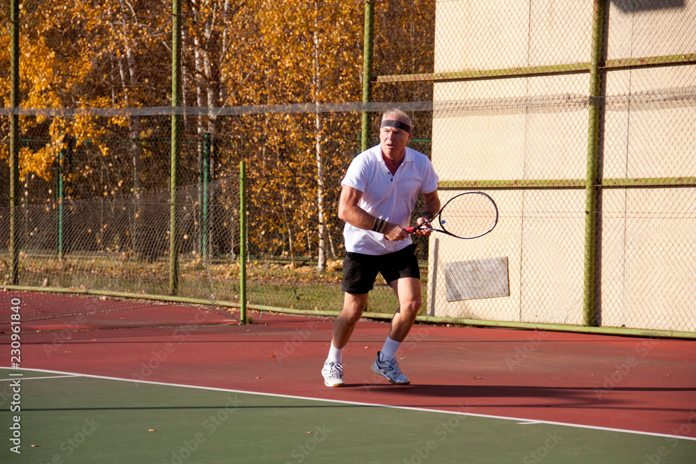 An elderly man over sixty plays tennis.