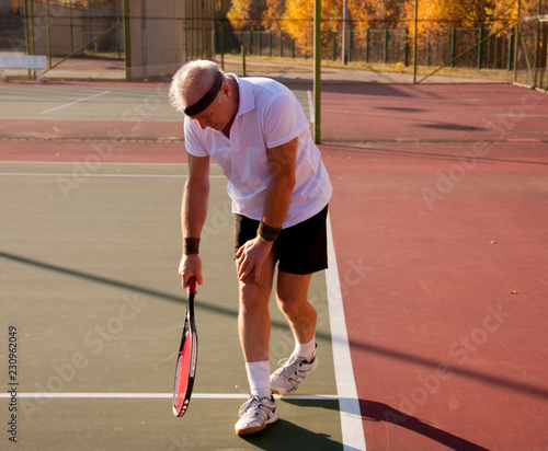 An elderly man over sixty plays tennis. © Дворецкая Таня