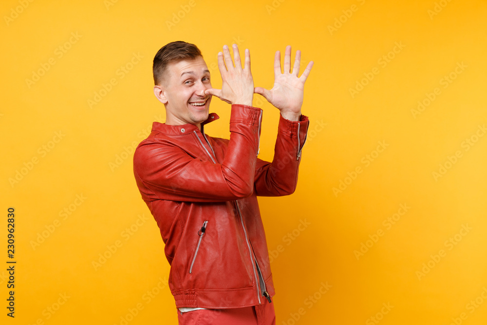 Portrait vogue smiling handsome young man 25-30 years in red leather jacket, t-shirt standing isolated on bright trending yellow background. People sincere emotions lifestyle concept. Advertising area Portrait vogue smiling handsome young man 25-30 years in red leather jacket, t-shirt standing isolated on bright trending yellow background. People sincere emotions lifestyle concept. Advertising area
