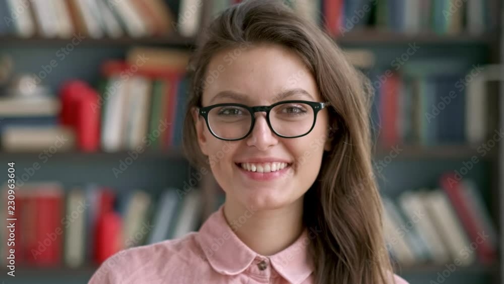 close up portrait of young pretty librarian woman smiling happy looking at camera in library bookshelf background knowledge learning. close up portrait of young pretty librarian woman smiling happy looking at camera in library bookshelf background knowledge learning.