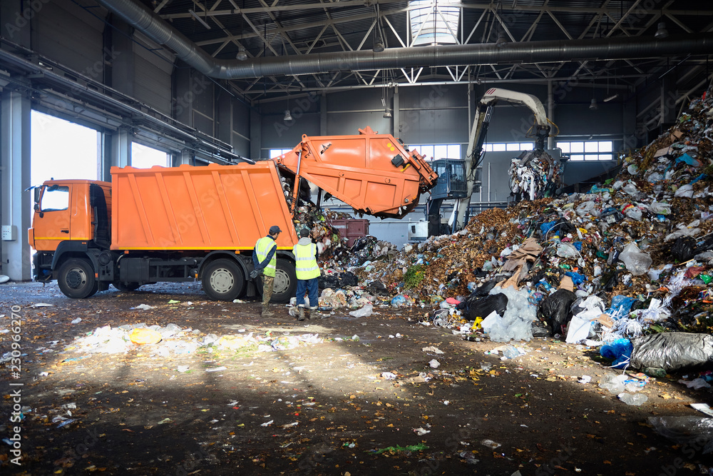 Two workers of recycling plant control process of unloading garbage