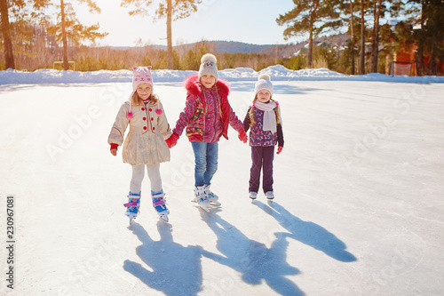 Three little girls skate on the ice. Vacations and holidays in nature