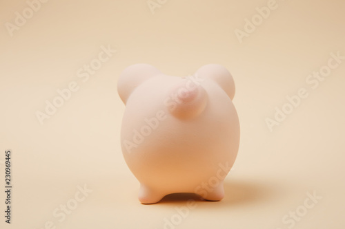 Close up photo, Back rear view of pink piggy money bank isolated on beige wall background. Money accumulation, investment, banking or business services, wealth concept. Copy space advertising mock up.