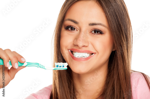 young woman brushing her teeth tooth brush on white background