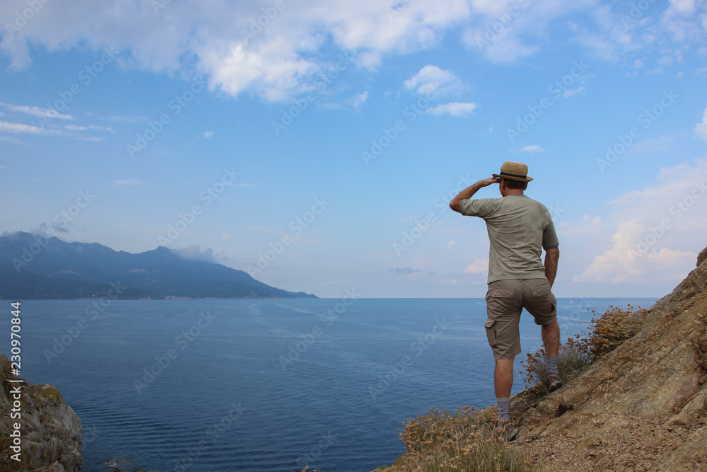 Man with straw hat enjoying the view in Elba island, Enfola headland, Italy Man with straw hat enjoying the view in Elba island, Enfola headland, Italy