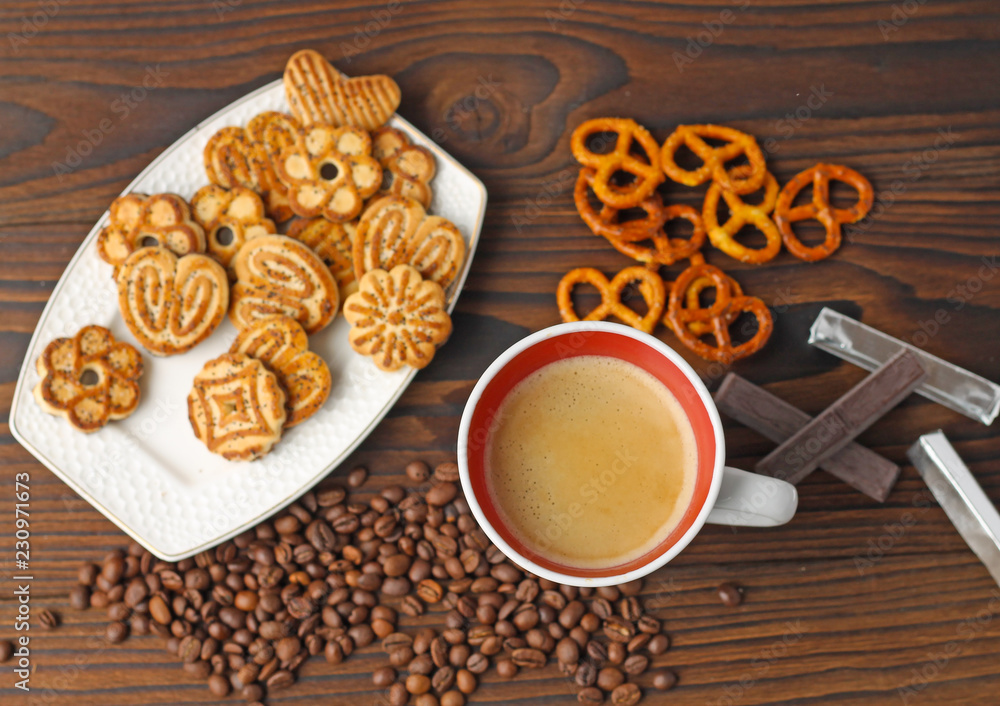 A cup of coffee, grains of coffee and cookies on a wooden table. A cup of coffee, grains of coffee and cookies on a wooden table.