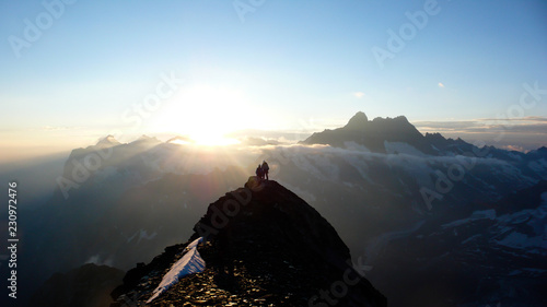 several mountain climbers on the famous Mittellegi Ridge on Eiger mountain in the Alps of Switzerkland heading to the summit at sunrise