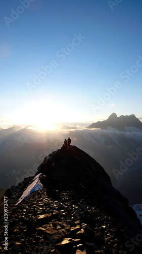 several mountain climbers on the famous Mittellegi Ridge on Eiger mountain in the Alps of Switzerkland heading to the summit at sunrise