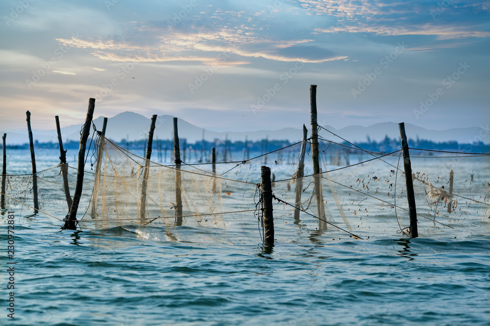 fishing net stretched in the sea at sunset background