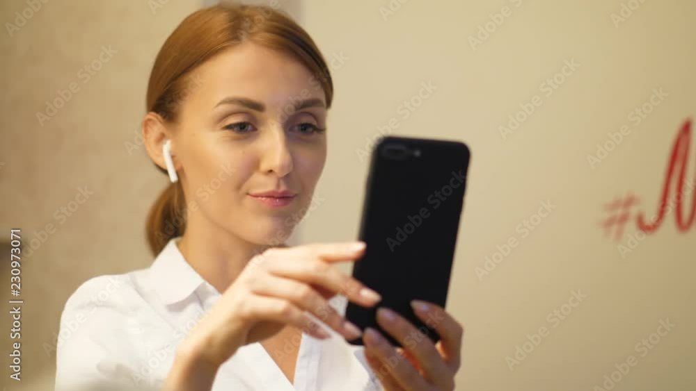 Portrait of young woman make video call, using smartphone and earpods Portrait of young woman make video call, using smartphone and earpods