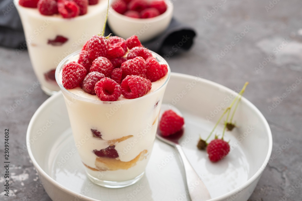 Tiramisu with raspberry in glasses on grey background. Italian dessert. Copy space. Tiramisu with raspberry in glasses on grey background. Italian dessert. Copy space.