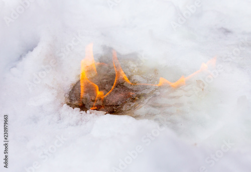 Flame of fire on white snow in winter