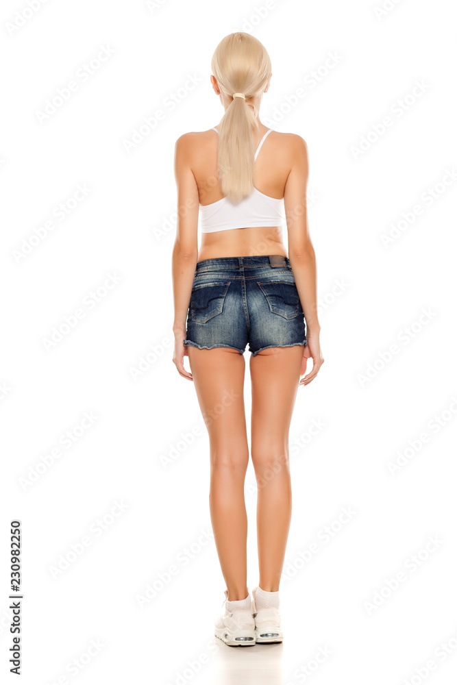 back view of young pretty blonde woman posing in short jeans on white background back view of young pretty blonde woman posing in short jeans on white background