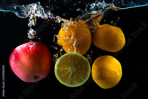 Fototapeta Naklejka Na Ścianę i Meble -  Various fruits clementine, lemon and apple splash of water on black