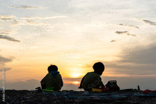 The silhouette brothers are playing together at the beach.