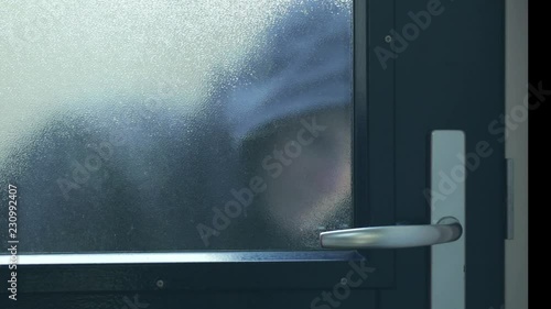 A female thief or a burglar breaking in into a private home.