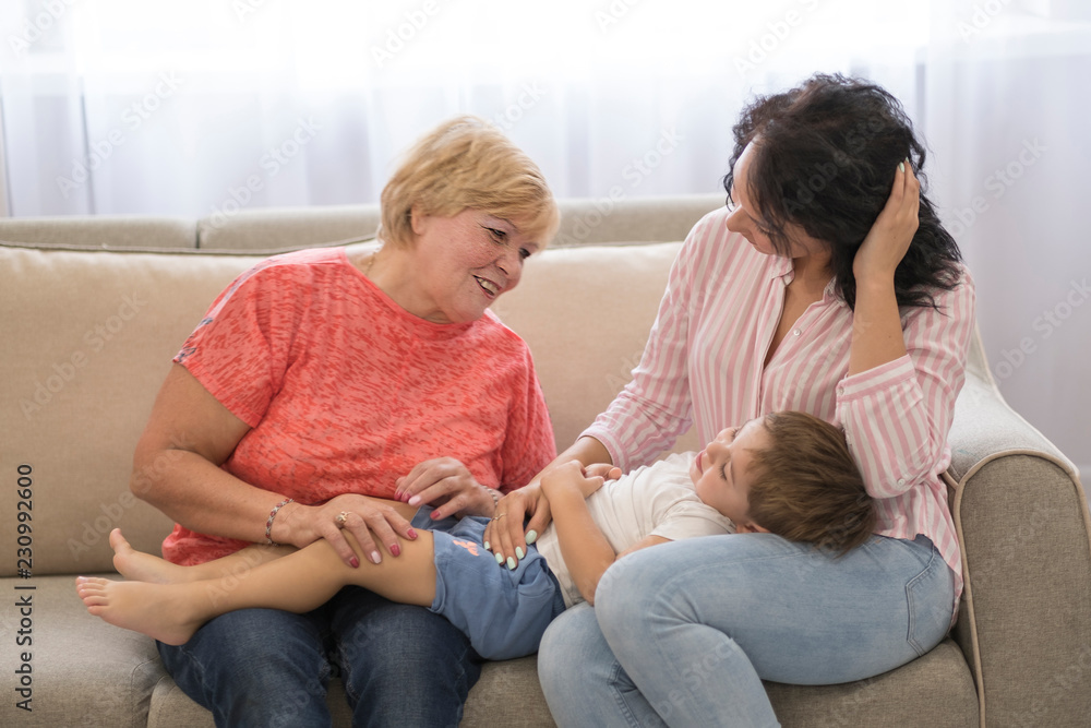 Nice family at home. Mother and grandmother with baby boy. Multi-generation family portrait. Close up of a generational family together in their living room at home, relaxing with the grandmother Nice family at home. Mother and grandmother with baby boy. Multi-generation family portrait. Close up of a generational family together in their living room at home, relaxing with the grandmother