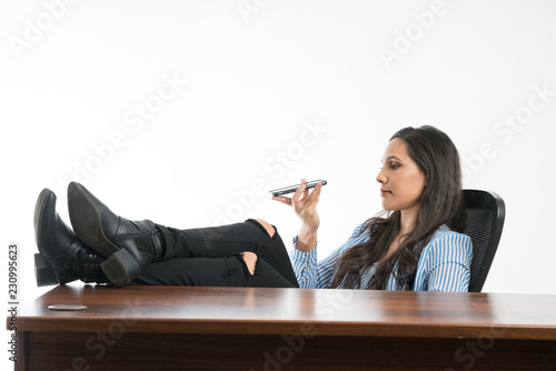 Woman checking if cellphone is ok  in the office, sitting with legs on desk