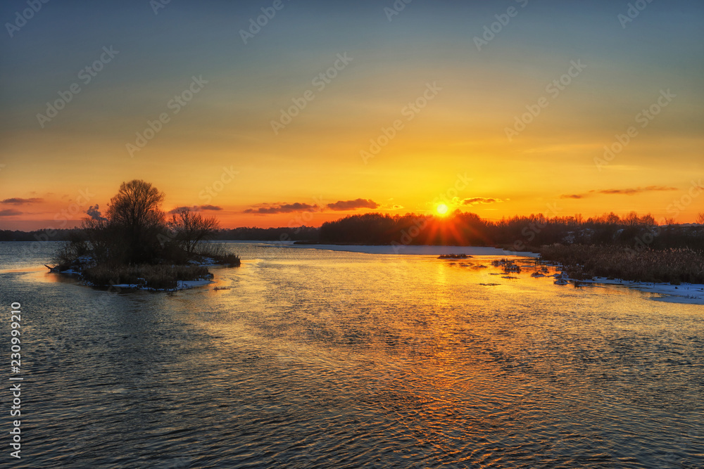 Beautiful russian early winter landscape with non frozen river, snow-covered riverside and small island at sunset. Scenic nature background Beautiful russian early winter landscape with non frozen river, snow-covered riverside and small island at sunset. Scenic nature background