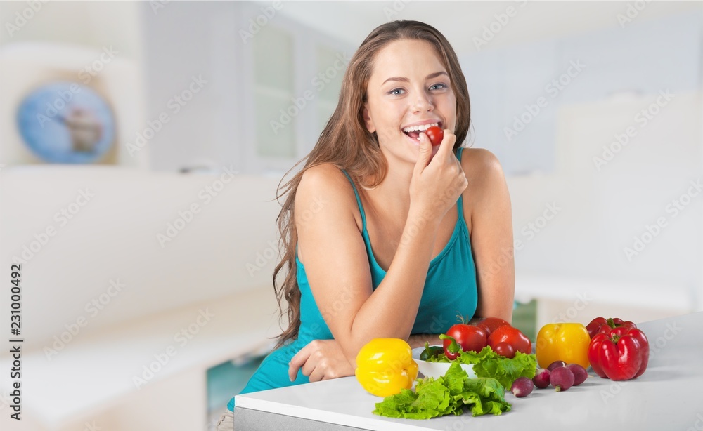 Young woman eating vegetables on blurred kitchen