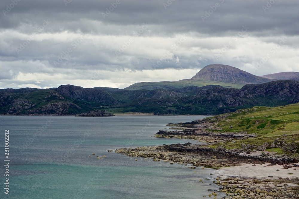 Mountains in the distance along the shore of Gruirnard Bay, on the west coast of the Highlands of Scotland. Mountains in the distance along the shore of Gruirnard Bay, on the west coast of the Highlands of Scotland.