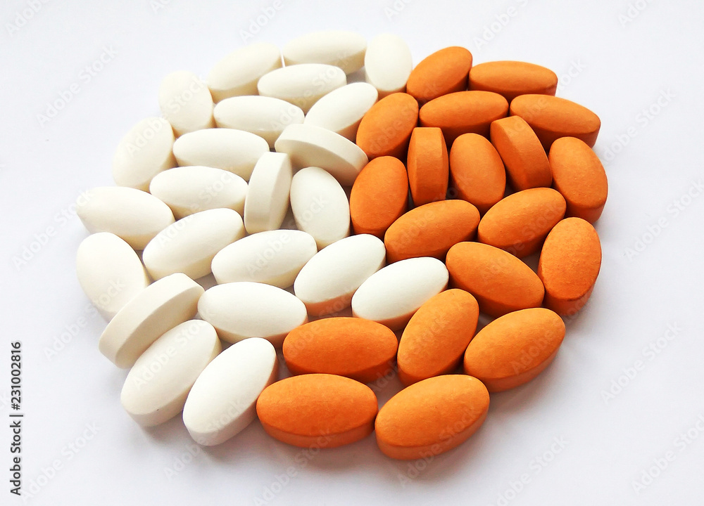 Assorted white and orange pharmaceutical medicine pills and tablets on white background. Pharmacy theme, health care, drug prescription for treatment medication and pharmaceutical medicament Assorted white and orange pharmaceutical medicine pills and tablets on white background. Pharmacy theme, health care, drug prescription for treatment medication and pharmaceutical medicament