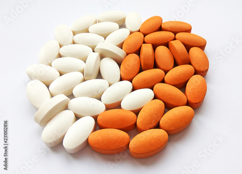 Assorted white and orange pharmaceutical medicine pills and tablets on white background. Pharmacy theme, health care, drug prescription for treatment medication and pharmaceutical medicament