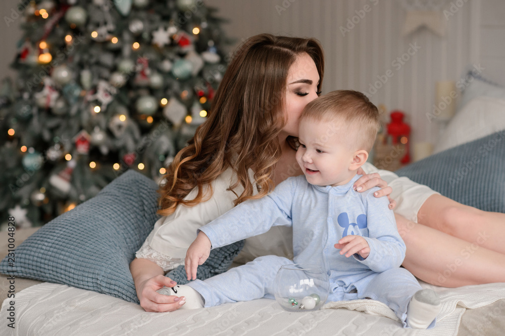 Merry Christmas celebration. Beautiful mom and little son at home near the Christmas tree. Christmas miracles. Merry Christmas celebration. Beautiful mom and little son at home near the Christmas tree. Christmas miracles.