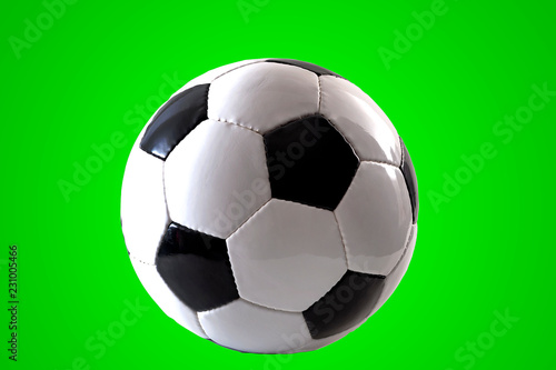 Sports equipment and leisure activity concept with a black and white generic classic leather football or soccer ball isolated on green background with a clip path cutout