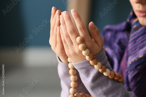 Photography Young Muslim woman with rosary beads praying at home, closeup