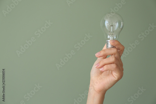 Female hand with eco light bulb on color background