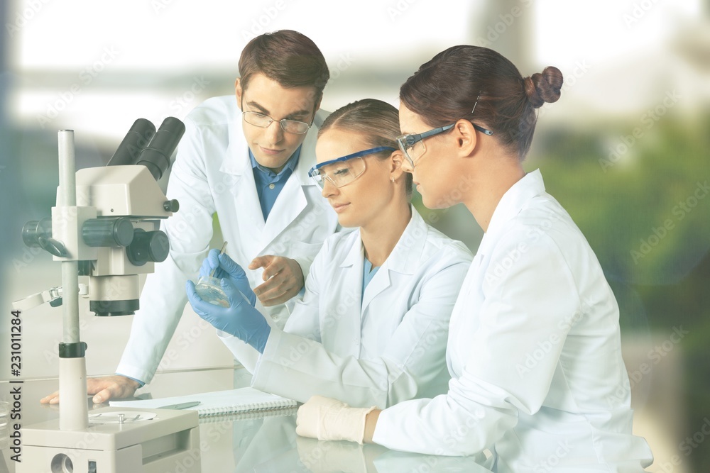 Female and male scientists in glasses working with microscope Female and male scientists in glasses working with microscope