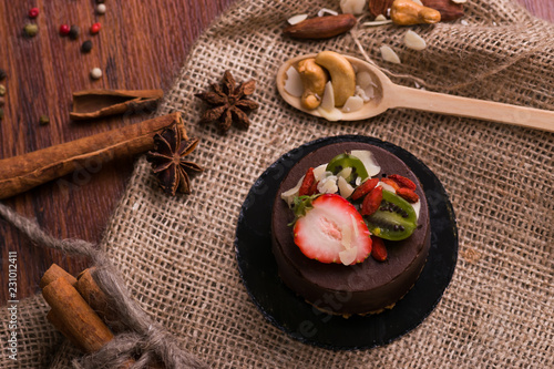 Cake with fruit on a wooden table and burlap. Dessert with berries, cinnamon and nuts