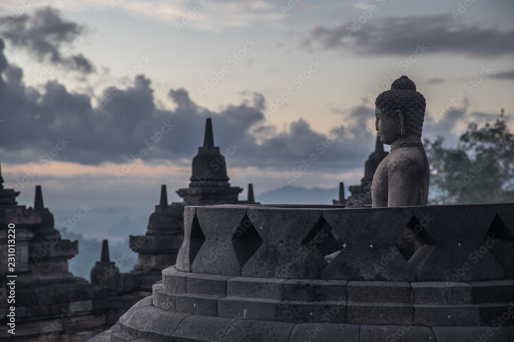 Sunrise and cloudscape at the Borobudur Temple in Java, with views of the Buddha statue and surrounding jungle in Indonesia