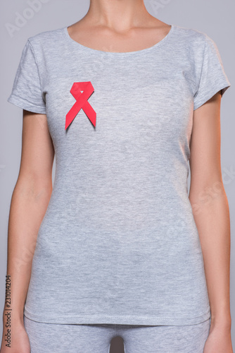 cropped shot of woman in grey tshirt with aids prevention red ribbon on grey background