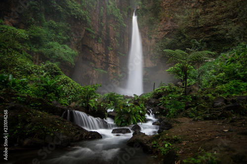 Dark and moody long exposure of the Kapas Biru waterfall in East Java, Indonesia photo