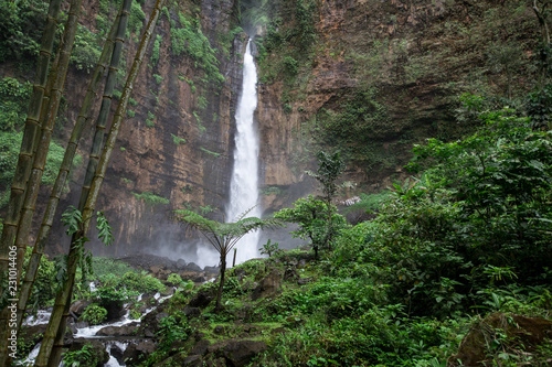 Thick jungle surround the Kapas Biru waterfall in East Java, Indonesia photo