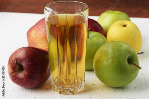  Apple juice in a glass and apples on the table.